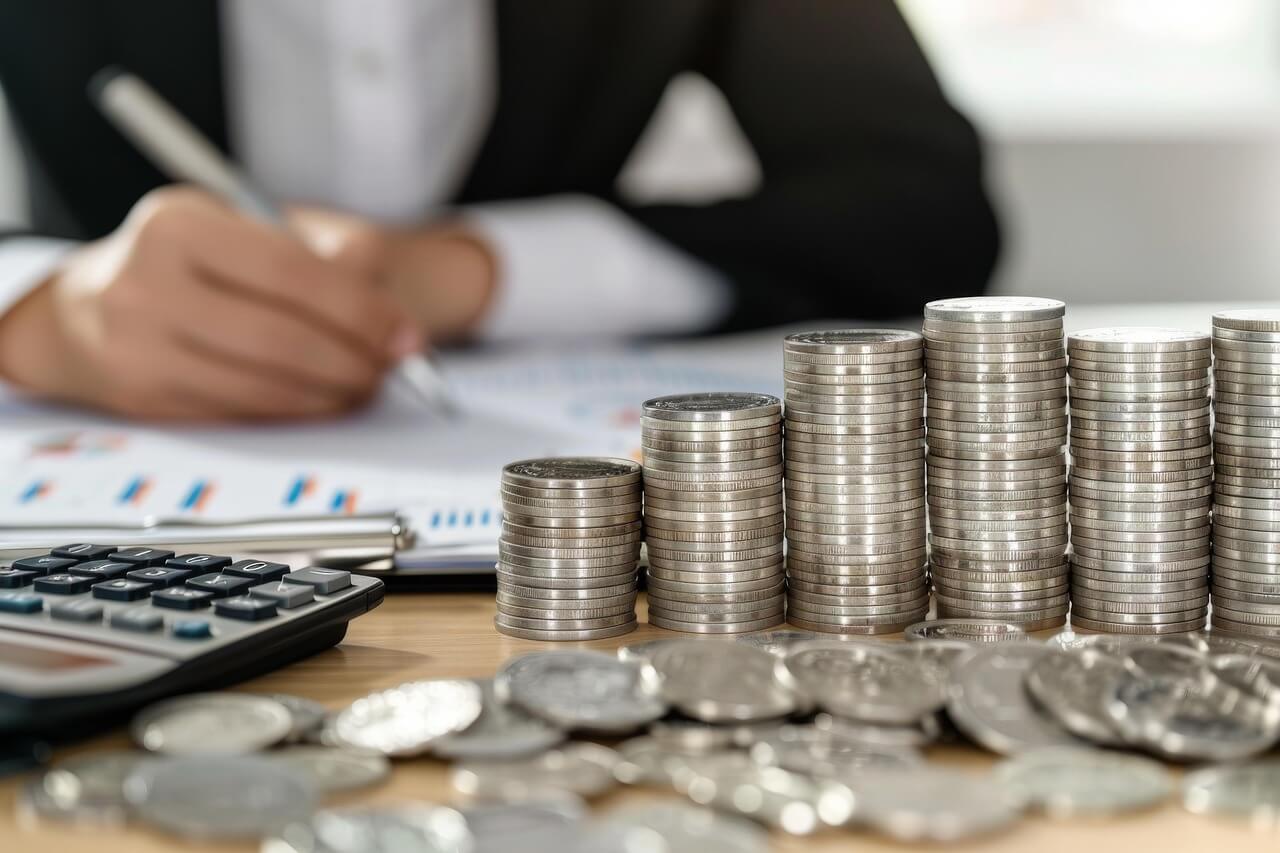 동전과 계산기, 재무 서류 위에 서명하는 모습으로 AI 회계 자동화와 회계사 직무 변화를 상징하는 이미지