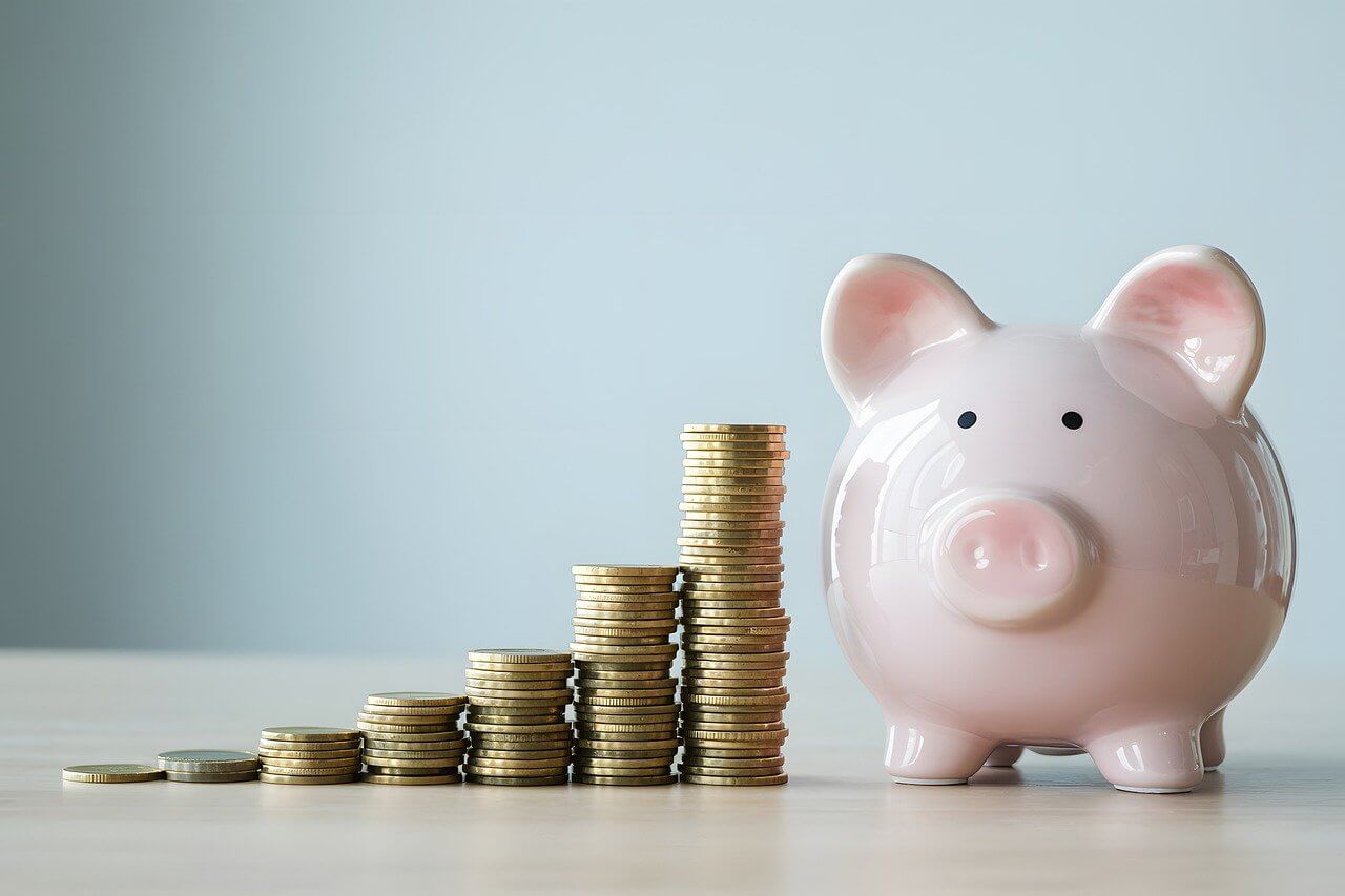 동전이 쌓여 있는 돼지저금통 이미지로 경제 성장과 생활 체감의 차이를 상징적으로 보여주는 사진